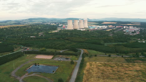 Hochwertige-Aufnahmen-Einer-Drohne,-Die-Sich-Einem-Kraftwerk-Nähert-Und-Detaillierte-Ansichten-Der-Schornsteine-Und-Der-Umgebung-Erfasst,-Um-Industrielle-Und-ökologische-Themen-Zu-Präsentieren.