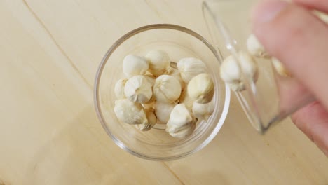 Pouring-cardamom-seeds-into-a-glass-bowl-in-slow-motion-from-a-top-down-view