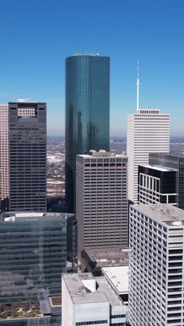 Toma-Vertical-Con-Dron-Del-Centro-De-Houston,-EE.-UU.,-Rascacielos-Y-Torres-Del-Distrito-Financiero-En-Un-Día-Caluroso-Y-Soleado