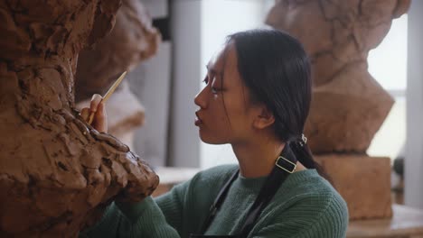 Una-Mujer-Profesional-Está-Concentrada-Y-Atenta-Mientras-Trabaja-En-Una-Escultura,-Sus-Manos-Dan-Forma-Y-Refinan-El-Material-Con-Destreza.