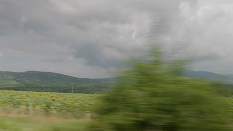 Side-view-from-moving-car-of-mountains-at-a-stormy-cloudy-day