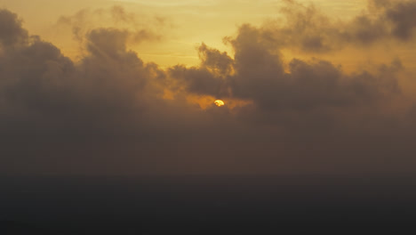 Golden-sun-setting-behind-dramatic-clouds-casting-warm-hues-over-the-horizon,-Sunset-in-Iceland