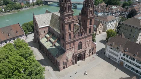 Vídeo-De-Dron-En-4K-De-La-Entrada-Y-La-Plaza-De-Una-Iglesia-Clásica-En-Basilea,-Suiza,-A-Lo-Largo-Del-Río-Rin