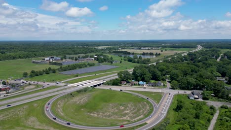 Aerial-footage-of-a-highway-intersection-with-lush-greenery-and-distant-buildings