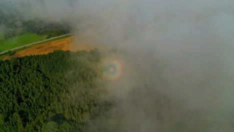 CIrcle-rainbow-in-dense-cloud-fog,-aerial-top-down-forest-agriculture-field