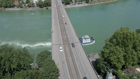 4K-Drone-Video-of-Tugboat-on-the-Rhine-River-Going-Under-the-Wettsteinbrücke-Bridge-in-Basel,-Switzerland