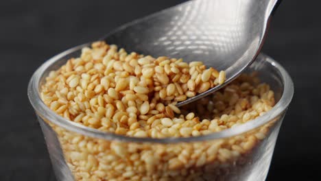 Sesame-seeds-being-scooped-from-a-glass-bowl,-slow-motion-close-up