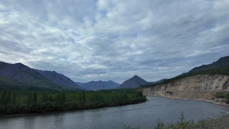 A-serene-river-meanders-through-lush-greenery-and-majestic-mountains-under-a-stunning-sky-filled-with-clouds-during-twilight-in-Yakutia