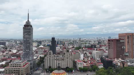 Torre-Latino-building-and-Palace-of-Fine-Arts-near-Alameda-Central-seen-from-descending-drone-flight,-overlooking-the-city