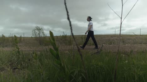 Man-walking-on-dirt-road-by-expansive-fields