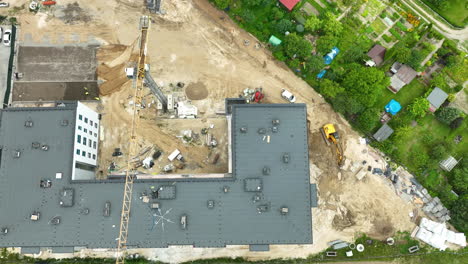 Vista-Aérea-De-Un-Sitio-De-Construcción-Con-Grúas-Y-Maquinaria-Trabajando-Activamente-En-Un-Gran-Complejo-De-Edificios-Rodeado-De-áreas-Verdes.