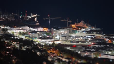 Eine-Malerische-Aussicht-Auf-Eine-Stadt-Bei-Nacht,-Mit-Hellen-Lichtern,-Die-Die-Uferpromenade-Und-Die-Städtischen-Strukturen-Hervorheben