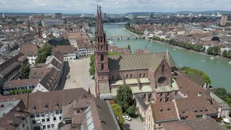 Vídeo-De-Dron-En-4K-De-Una-Iglesia-Histórica-Con-Dos-Torres-En-Las-Orillas-Del-Río-Rin-En-El-Centro-De-Basilea,-Suiza