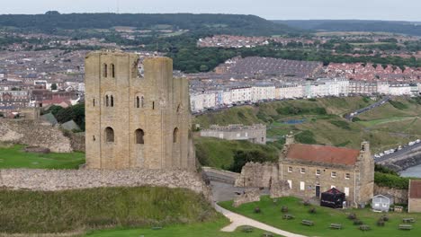 Aerial-drone-view-of-Scarborough-Castle-in-Scarborough,-North-Yorkshire-taken-early-morning-on-an-overcast-day-in-summer