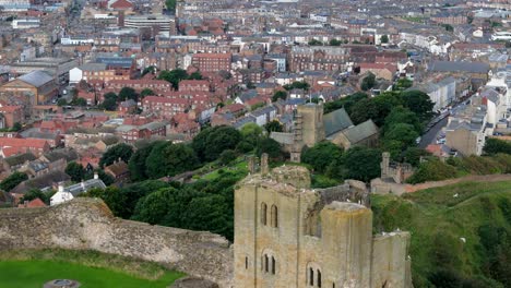 Aerial-drone-view-of-Scarborough-Castle-in-Scarborough,-North-Yorkshire-taken-early-morning-on-an-overcast-day-in-summer