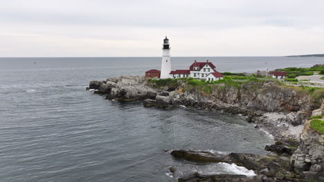 Historic-Portland-Head-Lighthouse-along-Maine-coastline,-aerial-forward-approach