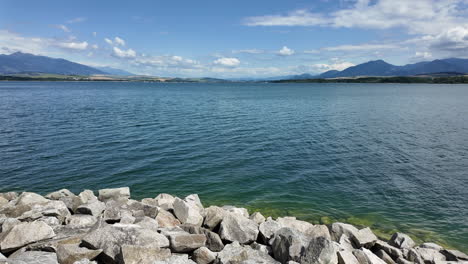 Peaceful-lakeside-with-clear-water-and-mountainous-horizon