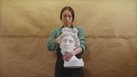 A-young,-fit-artist,-visibly-tired-but-determined,-holds-a-finished-statue