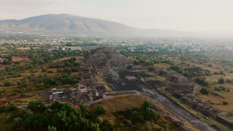 Scenic-aerial-overlooking-the-famous-Pyramid-of-the-Moon's-facade-and-the-Cougar-Mural,-Teotihuacan,-Mexico