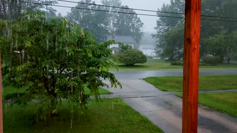 High-quality-footage-capturing-a-rainy-day-from-a-porch,-overlooking-a-serene-neighborhood-with-lush-greenery-and-wet-driveways