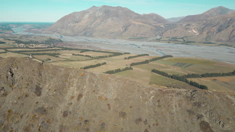 Hombre-Caminando-Por-La-Cresta-Rocosa-De-Una-Montaña-En-Canterbury,-Nueva-Zelanda.-Drone-Rastreando