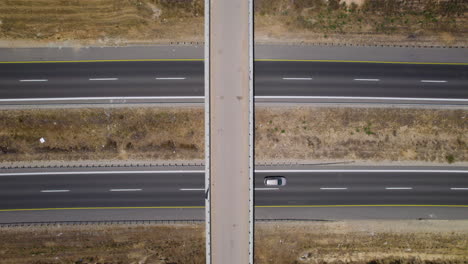 Vertical-top-down-timelapse-of-a-Farm-Bridge-Over-Highway-crossroads-in-summer,-Aerial-drone-view