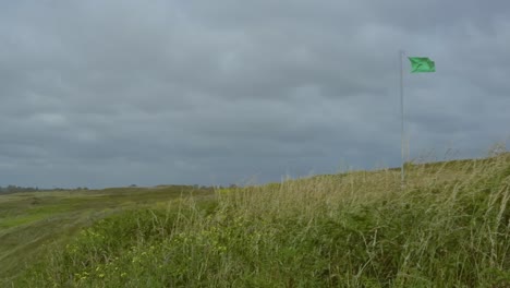 Cloudy-stormy-sky-on-the-coast-with-green-flag-for-surfing