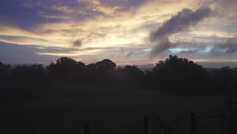 Captivating-sunset-scene-with-low-clouds-moving-right-and-high-clouds-drifting-left-over-a-silhouetted-forest