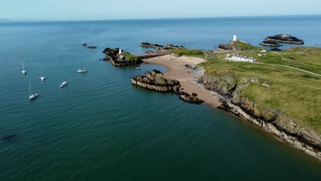 Luftaufnahme-Des-Friedlichen-Walisischen-Inselstrands-Ynys-Llanddwyn-Mit-Touristenyachten,-Die-An-Einem-Atemberaubenden-Ufer-Vor-Anker-Liegen