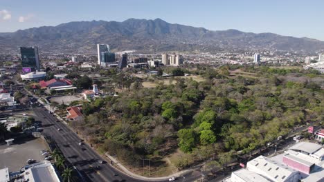 Aerial-view-of-La-Sabana-Metropolitan-Park-amidst-the-urban-landscape-of-San-Jose,-Costa-Rica-with-mountains-in-the-background