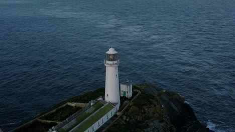 South-Stack-lighthouse-aerial-view-orbits-rugged-island-nautical-landmark-during-golden-hour-sunrise