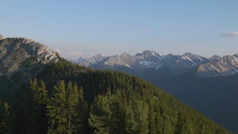 Schneebedeckte-Berge-Und-Dichter-Kiefernwald-Bei-Sonnenuntergang-Im-Banff-Nationalpark