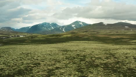 Aerial-trucking-pan-right-over-grassland-plains-and-mountains-of-Rondane-National-Park-Innlandet-county-Norway