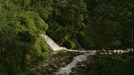 Rainforest-Waterfall-and-River-Scenery-in-Nepal,-Flowing-River-and-Small-Waterfall-Landscape-in-Tropical-Scenery-in-a-Forest-in-the-Himalayas-Mountains,-Green-Nepal-Nature-Shot-with-Lush-Greenery