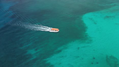 Tender-boat-gliding-over-vibrant-blue-ocean-waters-with-a-clear-sky-above