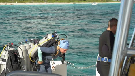 Divers-prepare-for-an-underwater-adventure-off-a-tropical-beach-in-clear,-blue-waters