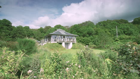 Crane-shot-reveals-house-in-countryside-surrounded-by-lush-woods-and-vegetation