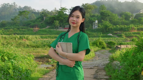 Portrait-of-young-female-woman-nurse-doctor-with-stethoscope-and-tablet-standing-in-rural-village-plantation-looking-in-to-camera-slow-motion-close-up-Asia-healthcare-system