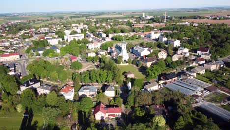 Aerial-panorama-of-Kietrz-featuring-the-Church-of-Saint-Thomas-the-Apostle-surrounded-by-residential-buildings-and-lush-greenery,-Poland