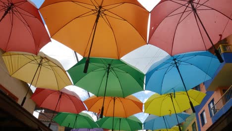 Walking-Under-Colorful-Umbrellas-in-Famous-Pedestrian-Street-in-Downtown-Guatape,-Colombia