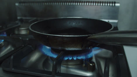 Beautiful-slow-motion-shot-of-a-frying-pan-preheating-with-a-burner-and-fire-in-an-industrial-kitchen-inside-a-restaurant