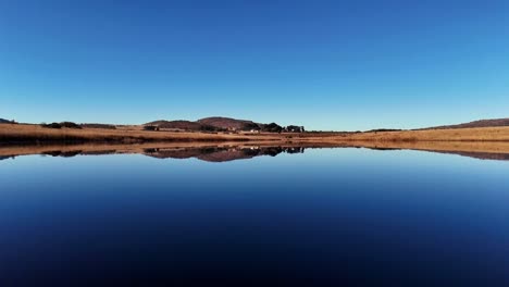 Vídeo-De-Vuelo-A-Baja-Altura-Sobre-Un-Lago-En-Un-Paisaje-Sereno,-Capturado-Con-Un-Dron-En-Un-Día-Sin-Viento