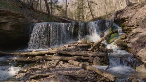 Water-cascades-over-a-rocky-ledge-in-a-forest-surrounded-by-trees