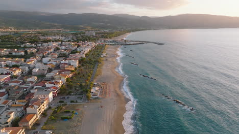 4K-Aerial-Slow-push-in-and-descend-of-beach-restaurant-Portorosa-at-sunset