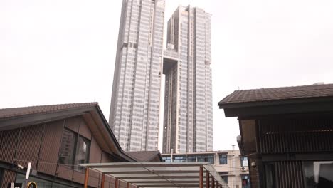 Modern-high-rise-building-towers-above-traditional-style-roofs,-contrasting-contemporary-architecture-with-historic-design-in-an-urban-setting