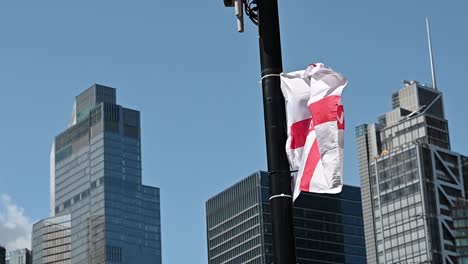 England-flag-in-front-of-the-City-of-London,-United-Kingdom