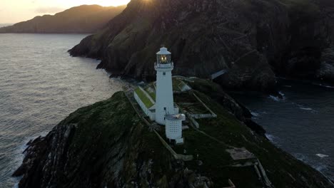 Luftaufnahme-Des-Leuchtturms-South-Stack,-Der-Die-Insel-Als-Wahrzeichen-Umkreist-Und-Die-Berge-Beim-Sonnenaufgang-Enthüllt