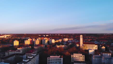 Aerial,-rising,-drone-shot-overlooking-buildings-and-the-church-in-Turku-city,-during-sunset,-in-Varsinais-suomi,-Finland