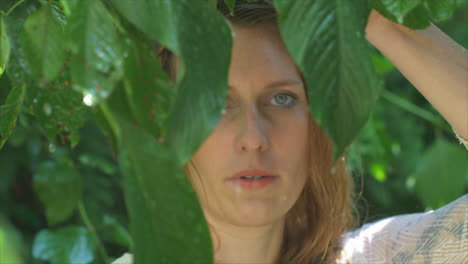 young-woman-standing-in-rain-surrounded-by-greenery