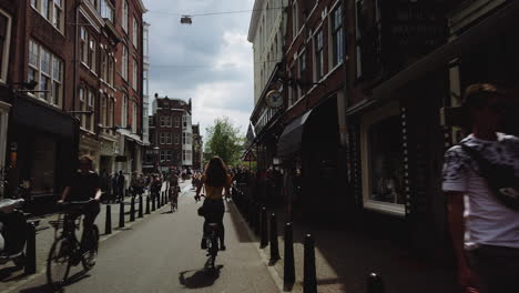 Slow-motion-shot-of-a-woman-biking-down-the-street-in-Amsterdam,-Netherlands